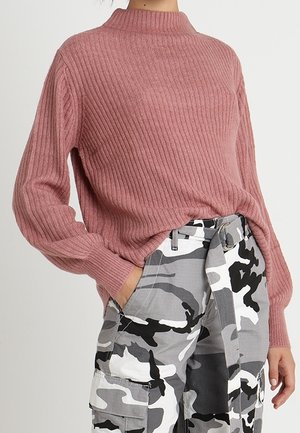 Ribbede støvede rosa langærmede sweater kombineret med højtaljede, hvide, grå og sorte camouflage cargobukser med stofbælte.