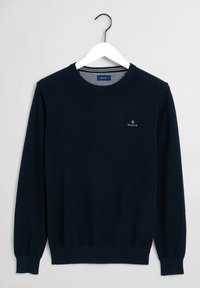 Granatowy dzianinowy sweter z prążkowymi mankietami i dołem; na piersi znajduje si�ę małe białe logo GANT, a fason ma klasyczny okrągły dekolt.