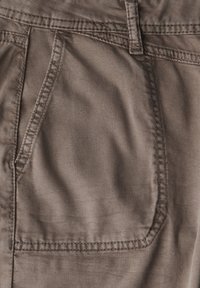 Pantalones de algodón marrones con un bolsillo frontal, que presentan detalles de costura visibles y un acabado de tela texturizada.