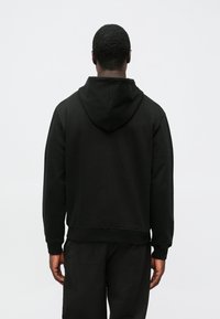 Μαύρο φούτερ με κουκούλα, με άνετη εφαρμογή, απαλή υφή υφάσματος και ριμπ μανσέτες και τελείωμα, εμφανιζόμενο από πίσω.