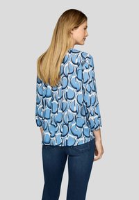 Leichte Bluse mit einem blau-weißen abstrakten Muster, langen Ärmeln mit elastischen Bündchen und lockerer Passform.