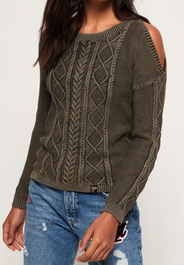Svetr z pletené olivově zelené vlny s otevřeným designem ramen, zdobený texturovaným kabelovým vzorem a žebrovanými manžetami. Kombinovaný s roztrhanými džíny.