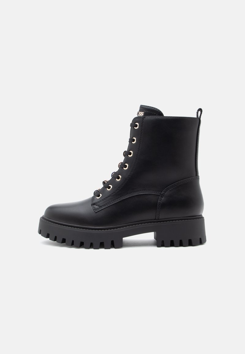 Botins de couro preto até ao tornozelo com sola robusta, ilhós dourados e costura reforçada. Inclui uma alça para facilitar o calçar.