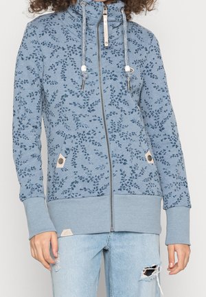 Hellblauer Reißverschluss-Hoodie aus weichem Stoff mit einem Blumenmuster in dunklerem Blau, zwei Fronttaschen und elastischen Bündchen.