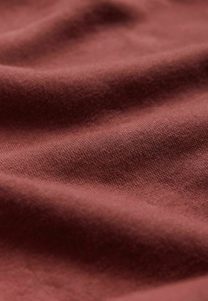 Material din bumbac texturat, într-o nuanță bogată de teracotă, cu un finisaj neted și o cădere delicată, având variații subtile de tonalitate.