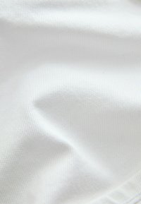 Prim-plan cu material alb neted, cu pliuri subtile și textură fin țesută.