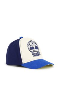 Cappellino da baseball blu e crema con visiera arrotondata, tessuto testurizzato e logo Timberland sulla parte frontale. Fascia regolabile in plastica sul retro.