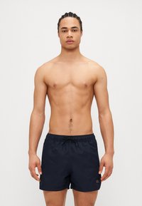 Shorts de bain navy en tissu léger avec une taille élastique et un cordon de serrage, ornés d'un petit logo sur le devant.