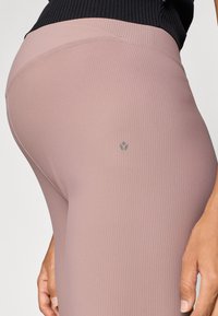 Ροζ ανοιχτό ριμπ κολάν με διακριτική λεπτομέρεια λογότυπου κοντά στη μέση, με λεία και ελαστική υφή.