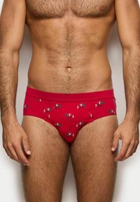 Czerwone slipy męskie z zabawnym wzorem rysunkowych postaci, wykonane z elastycznego materiału o gładkiej fakturze i miękkim pasku.