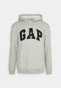 Felpa grigia con cappuccio caratterizzata da un logo nero "GAP" sul petto, cappuccio con coulisse e tasca frontale a marsupio. Tessuto morbido e texture.