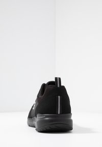 Svart träningsskor med överdel av mesh, texturerade paneler och reflekterande detaljer. Har dämpad sula och dragflik för enkel påtagning.