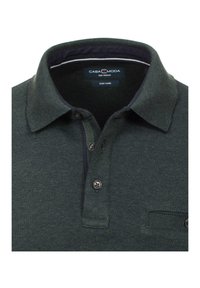 Dunkelgrünes Poloshirt aus strukturiertem Stoff mit einem marineblauen Kragen, zwei Knöpfen und einer Brusttasche. Das Etikett lautet "CASA MODA, Größe Mittel, Pflegeleicht."