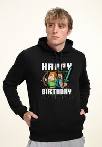 Sudadera negra con un gráfico de personajes cuadrados sosteniendo armas y el texto "FELIZ CUMPLEAÑOS" en blanco, con acentos verdes en el diseño.