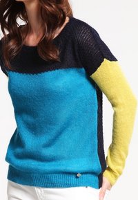 Färgglad stickad tröja med turkos kropp, marinblå övre del och gula ärmar. Mjuk textur med rund halsringning och sidodetalj.
