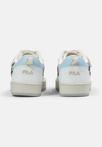 Baskets en cuir blanc avec un accent bleu clair au talon, semelle plate, détail perforé noir et logo FILA à l'arrière.