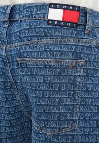 Jeans iz jeansa s toniranim printom "TOMMY JEANS" logotipa. Modra tkanina z oranžnim šivanjem, oznaka pri pasu z barvami blagovne znamke.