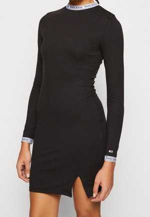 Zwarte lange mouw jurk met hoge halslijn, featuring een zijsplit en gemerkte manchetten met blauwe en witte accenten. Soepele, aansluitende pasvorm.