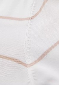 Witte stof met een subtiel ruitpatroon in lichtbeige, met textuursteken langs de naden voor extra detail.