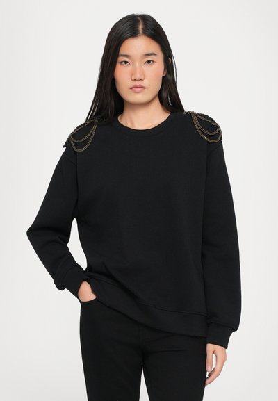 Czarna bluza z długim rękawem, z łańcuszkami na ramionach, okrągłym dekoltem i luźnym krojem. Wykonana z miękkiego materiału z teksturowymi akcentami.