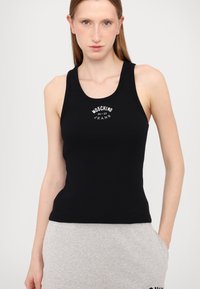 Juodas raižytas marškinėlių topas su apvaliu iškirpimu ir baltu spaudiniu. Dizainas yra prisitaikantis prie kūno ir turi plačias pečių juostas.