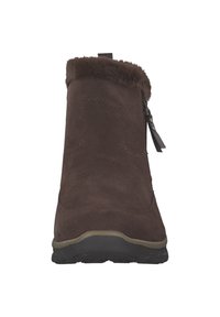 Bruine suède enkellaars met nep bontkraag, ritssluiting aan de zijkant en een rubberen profielzool. Heeft een gladde afwerking en een afgeronde neus.