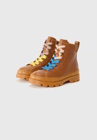Bottes en cuir marron à chevilles avec des semelles en caoutchouc texturé. Équipées de lacets colorés : jaune, bleu, orange et gris. Onglet de traction à l'arrière.