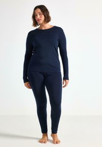 Mørkeblå, langærmet top og matchende leggings lavet af glat, blødt materiale med en tætsiddende design. Enkel udskæring, ingen mønstre eller accenter.