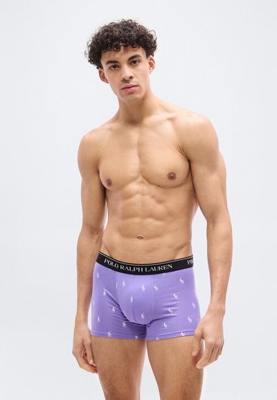 Νέος μυώδης άνδρας που φοράει μοβ Boxer briefs Polo Ralph Lauren με λευκά λογότυπα, σε απλό ανοιχτό φόντο.