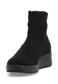 Stivaletto nero realizzato in morbido tessuto con un design snello e elastico. Presenta una suola piatta e dettagli di cucitura minimi.