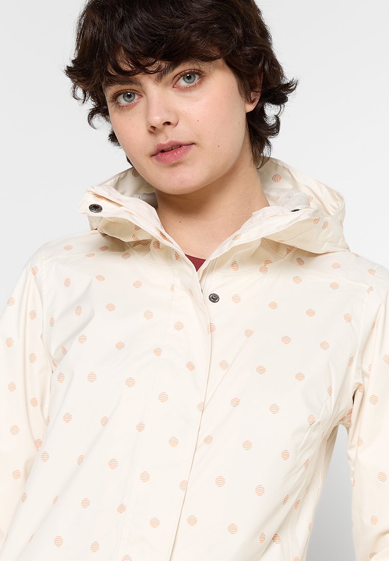 Lichtgewicht, waterdichte jas van crème met een capuchon, voorzien van verspreide perzikkleurige cirkelpatronen en drukknoopsluitingen.