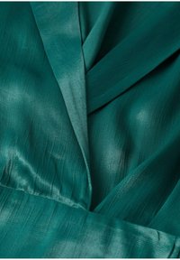 Tissu en satin sarcelle avec un col plié et une légère brillance, montrant une texture fine et des couches superposées.