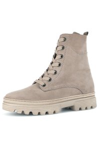 Bota de tobillo de ante beige con diseño de cordones, puntera redonda, cuello acolchado y suela de goma gruesa con un dibujo texturizado para tracción.