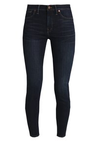 Tmavě modré skinny džíny s vysokým pasem, vybavené zipovým zapínáním, kovovým knoflíkem a jemným kontrastním šitím. Hladká textura.