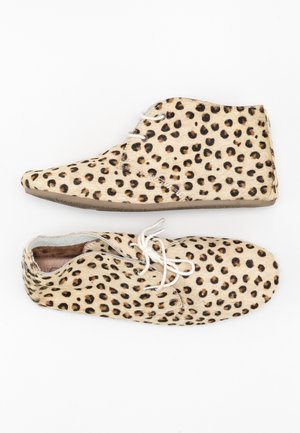 Buty w panterkę wykonane z teksturowanej futrzanej tkaniny, z zaokrąglonym noskiem, białymi sznurowadłami i podeszwą z neutralnego, gumowego materiału.