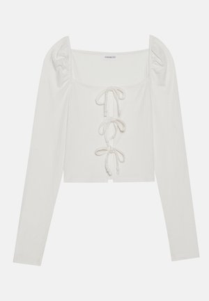 Top blanco de manga larga acanalada con escote cuadrado, mangas abullonadas y detalle de cordones en la parte frontal con lazos delgados. Diseño cropped.