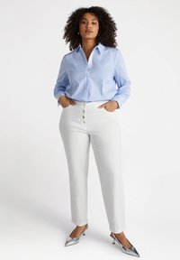 Lichtblauw gestreepte overhemd met lange mouwen, gecombineerd met witte hoge taille broek met zilveren knoopdetails en zilveren hakken.
