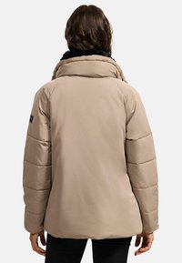 Beige padded jacket with a high collar, featuring a black faux fur lining and ribbed detailing on the sleeves. Smooth texture and relaxed fit.