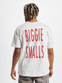 Hvid bomulds t-shirt med fed rød tekst på ryggen, der står "BIGGIE SMALLS." Korte ærmer og en afslappet pasform.