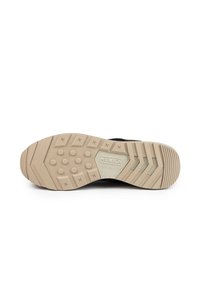 Semelle de sneaker noire avec semelle en caoutchouc beige, présentant un motif hexagonal, marquage "MUNIC", et un design texturé pour l'adhérence.