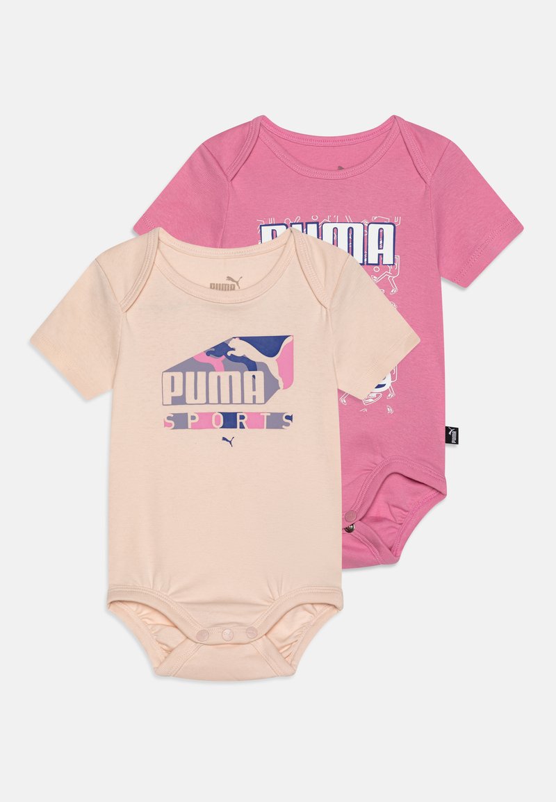 Dva kratka bodija za dojenčke v breskevni in roza barvi, z logotipom blagovne znamke Puma. Obe sta iz bombaža, z gumbi na dnu.
