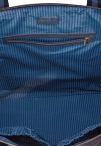 Blauw gestreepte stoffen binnenkant van een tas met een ritsvak, merklabel en een gladde textuur. Tasontwerp, donkere tinten en net stiksel.