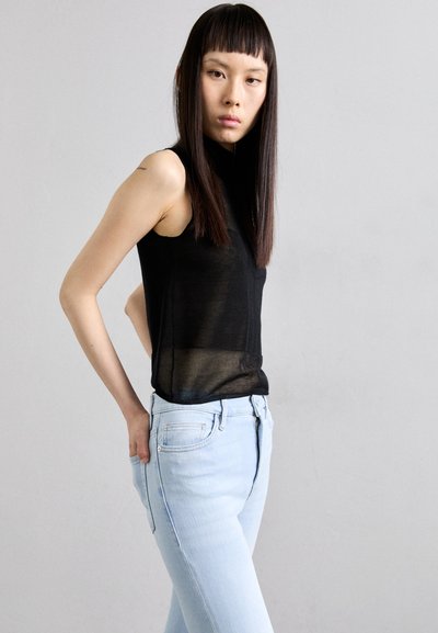 Svart ermeløs topp med en semi-gjennomsiktig tekstur, kombinert med lyseblå, slim-fit jeans i denim med frontlommer og knappelukking.