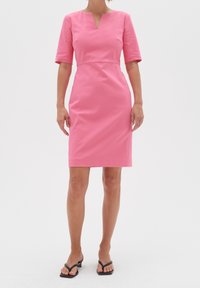 Rosa figurnära klänning med V-ringning, korta ärmar och knälång fåll. Tillverkad av slät tyg, med en enkel design utan mönster.