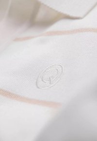 Valkoinen puuvillakangas, jossa on hienovaraiset beige raidat ja brodeerattu logo. Materiaali on sileä ja pehmeä. Kauluksellinen malli.