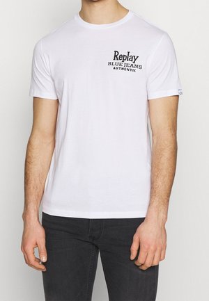 Hvid bomulds-T-shirt med et sort grafisk logo "Replay Blue Jeans Authentic" på venstre bryst. Korte ærmer og rund halsudskæring.