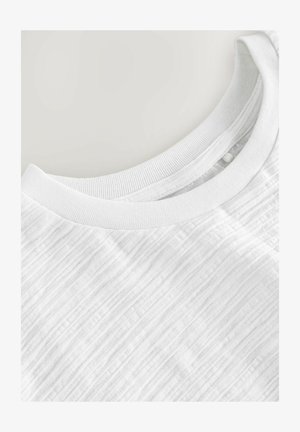 Balta īsām piedurknēm T-kreklā ar ribinātu apaļu kakla izgriezumu un teksturētu, nedaudz svītrainu auduma rakstu. Mīksts un viegls materiāls.