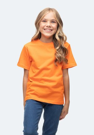 T-shirt en coton orange à manches courtes et col rond, associé à un jean en denim bleu, présentant une texture lisse et uniforme.