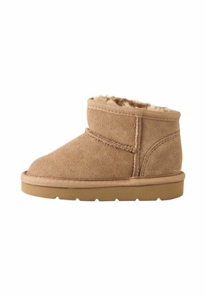 Short tan suede boot with visible stitching, soft fur lining, and a flat rubber sole.