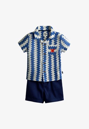 Detská košeľa s krátkym rukávom na gombíky, modro-biely cik-cak vzor a červený krab na vrecku, doplnená jednofarebnými tmavomodrými šortkami.